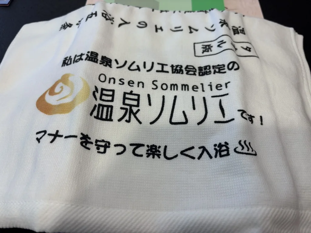 The white course towel printed with the Onsen Sommelier Association's logo and the words: I am an Onsen Sommelier certified by the Onsen Sommelier Association