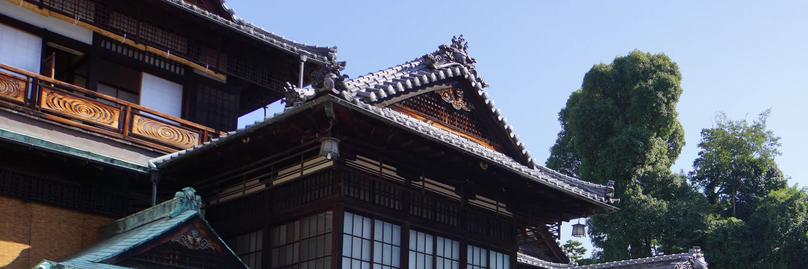 松山・道後温泉本館の、幾重にも重なる瓦屋根と彫刻の入った木の欄干